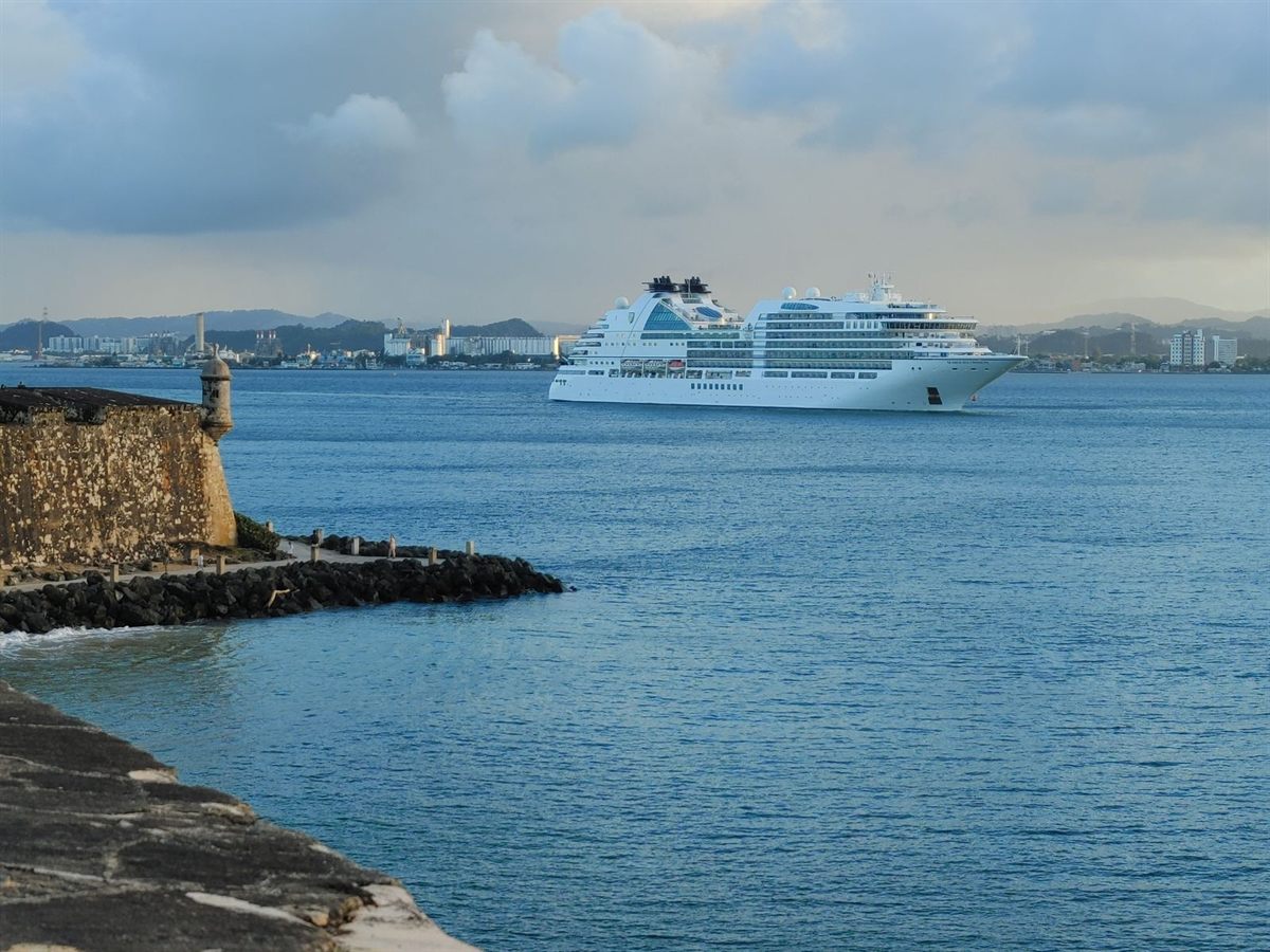 A cruise ship passing an old stone fort at a harbour entrance