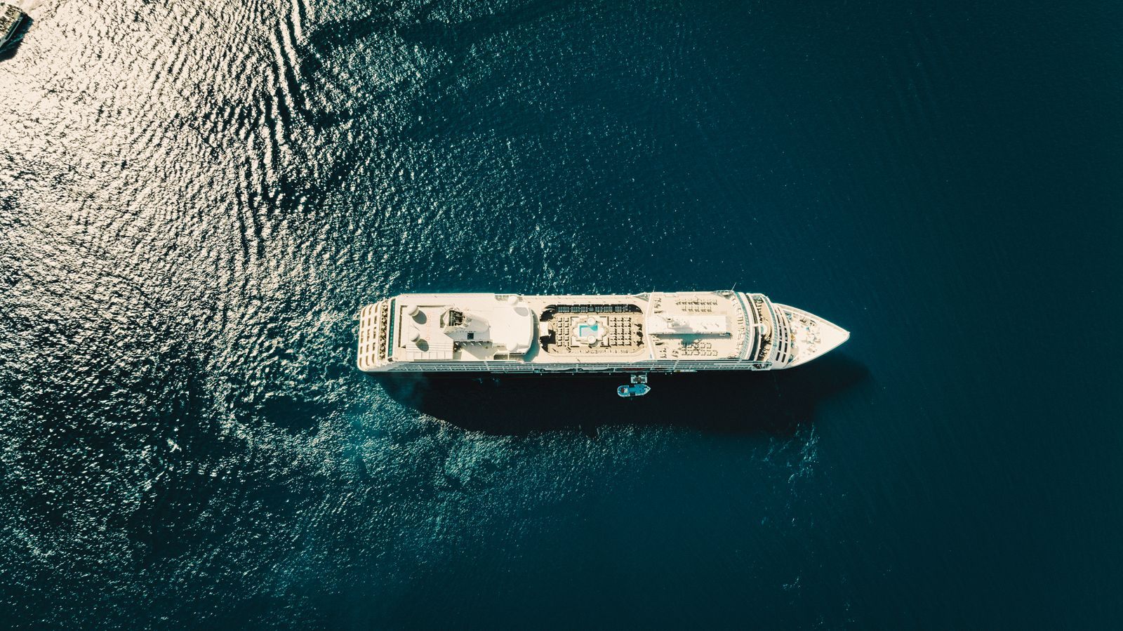 A cruise ship crossing a dark blue sea, seen from above: the cheapest cruise prices follow patterns