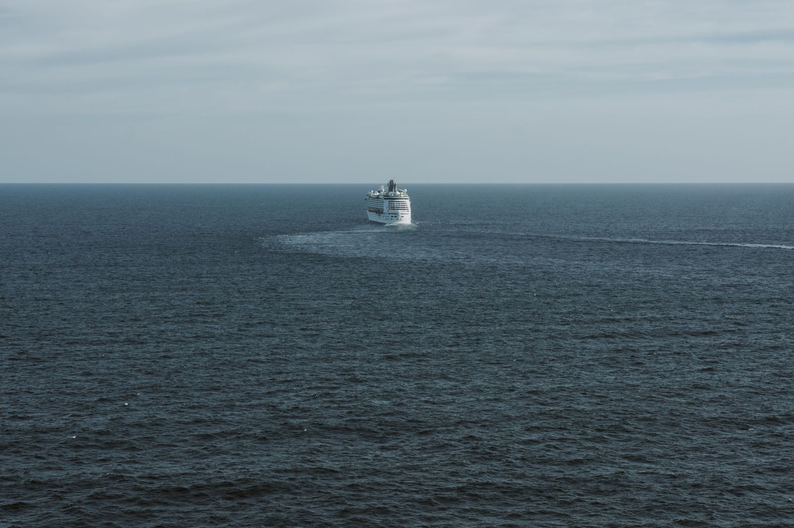 A cruise ship alone on a grey open sea, the long ocean crossings of repositioning cruises